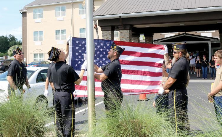 American Legion Post 57 Honor Guard members and members of the Liberty Division Sea Cadets, raise a new flag at the Best Western Plus hotel in Lake City on Friday morning in front of a group of onlookers such as other Post 57 members, hotel staff and hotel guests. (TONY BRITT/Lake City Reporter)