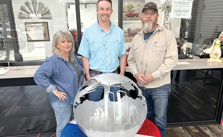 Rhonda Anderson (from left) stands with Kent Banner, Columbia County Assistant Supervisor of Elections, and Darryl Thomas, Columbia High School welding instructor, as the school’s welding piece, ‘Globe of Freedom,’ is on display at the Columbia County Supervisor of Elections Office. (COURTESY)