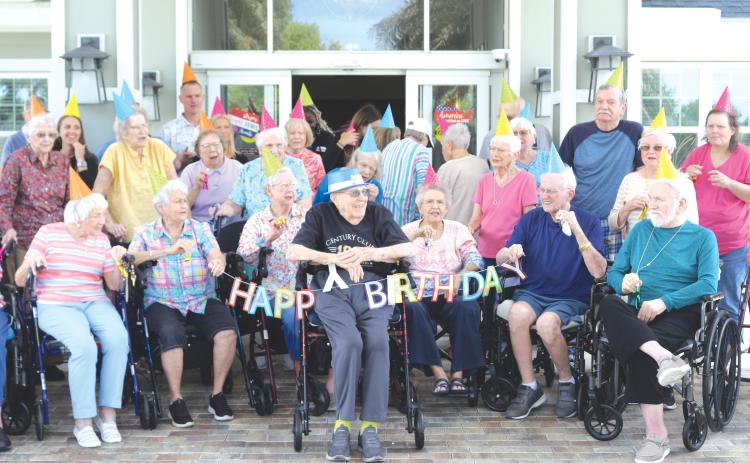 Del Porter (center) is all smiles as The Heron on Lake City residents wish him a happy 100th birthday on Thursday afternoon. (TONY BRITT/Lake City Reporter)