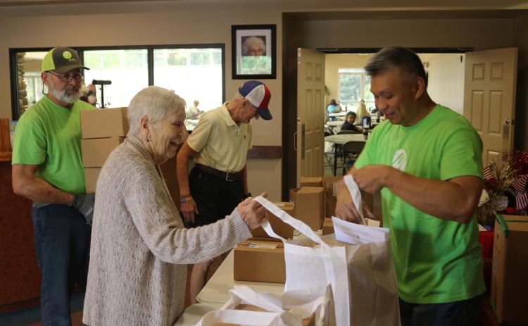Donna Kite (left) is aided by FPL employee Chi Lui as she gets a bag of hurricane meals while at the Lifestyle Enrichment Center on Wednesday afternoon. FPL provided bags for 153 seniors during the session. (TONY BRITT/Lake City Reporter)