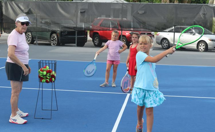 Marcia Kazmierski (left) watches as Jensen Haire, 8, hits a tennis ball during the 10th annual James Montgomery Tennis Camp at Youngs Park on Thursday. (TONY BRITT/Lake City Reporter)