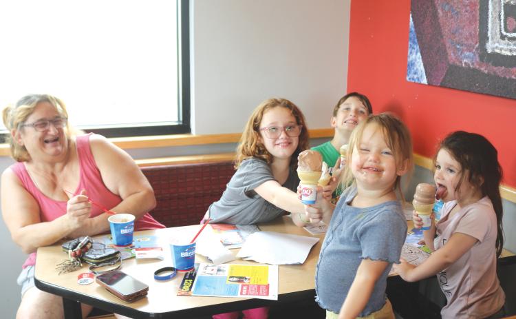 Bralen Peavy (foreground), 2, flashes a smile with chocolate on her face as she and Nevaeh Peavy (far right), 3, enjoy a cone of ice cream during the Cops-N-Cones event on Tuesday afternoon at Dairy Queen. (TONY BRITT/Lake City Reporter)