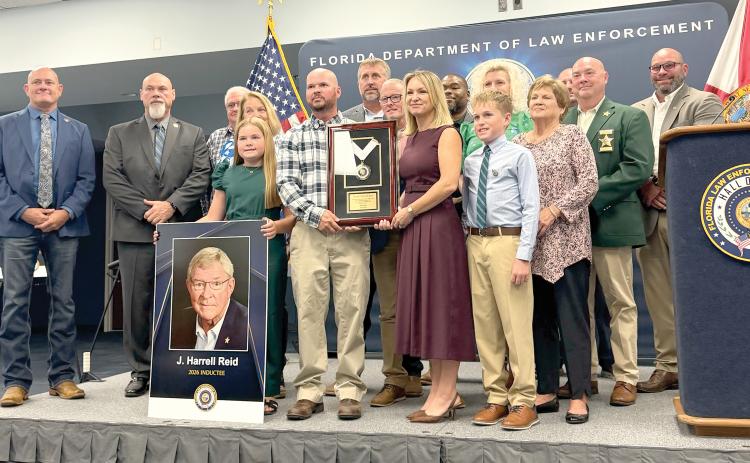 Kathryn Land and J. Reid, former Hamilton County Sheriff Harrell’s Reid’s children, hold his encased medallion after he was posthumously inducted into the Florida Law Enforcement Officers Hall of Fame on Saturday. Land and Reid were surrounded by family members and past and present members of the Hamilton County Sheriff’s Office. (COURTESY)
