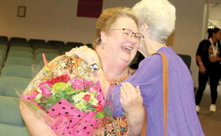 Karla Hatcher (left) gets a hug from Martha Ann Ronsonet at Tuesday’s Columbia County School Board meeting as one of five former educators honored at the district’s Teacher of a Lifetime ceremony. (TONY BRITT/Lake City Reporter)