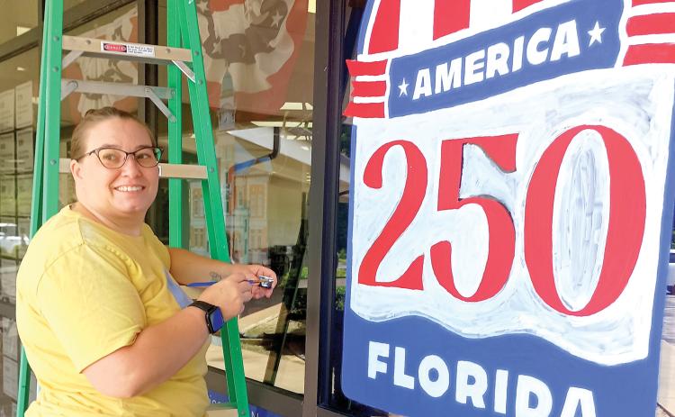 Artist Maggie Wilburn finishes up her America 250 art work on the Suwannee River Regional Library’s Live Oak branch ahead of the July 4 holiday. (ROB WOLFE/Lake City Reporter)