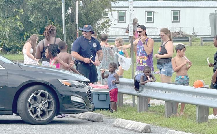 Lake City firefighter Earl Lupardus hands out popsicles to children at the Lake City Fire Department’s ‘Pop-Up Community Sparh Party’ at Annie Mattox Park on Friday. (COURTESY LAKE CITY FIRE DEPARTMENT)