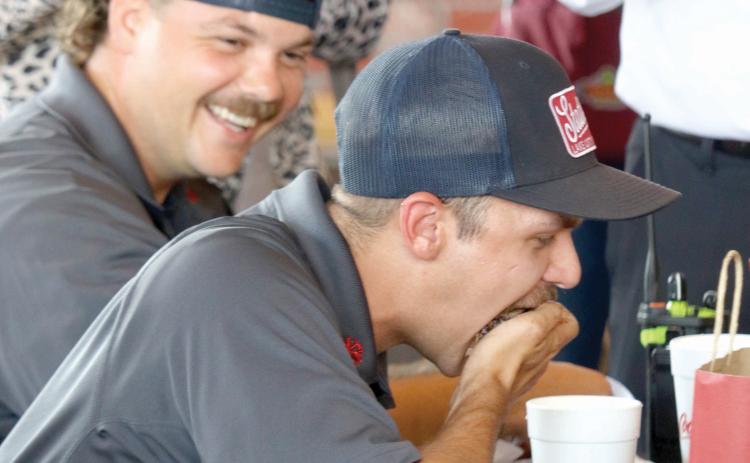 Lake City Firefighter Jerney Morgan (foreground) gets encouragement from Leon Jones as Morgan stuffs a handful ribs into his mouth during Tuesday’s rib-eating contest at Texas Roadhouse. (TONY BRITT/Lake City Reporter)