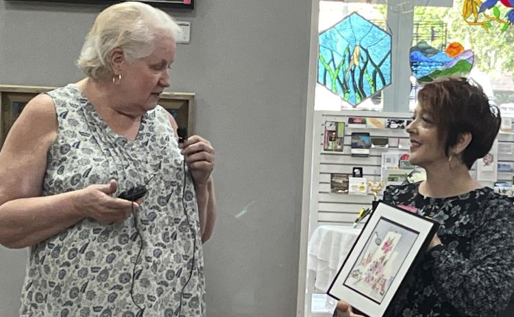 Artist Susan Guerry, of Bell, details her inspiration of her watercolor, to Gateway Art Gallery Curator Sheila Carr at the recent opening reception. She was using the terms  ‘structural chaos’ and ‘harmony’ — two seemingly opposite choices. (COURTESY)