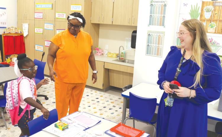 Jordynn Cray (left) prepares to get settled into the kindergarten classroom of Brittany Townsend (right) during the first day of classes at the new Eastside Elementary School. (TONY BRITT/Lake City Reporter)
