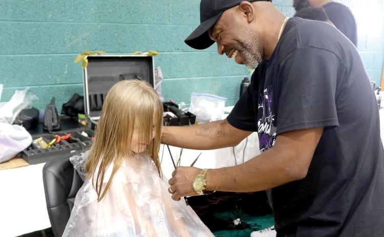 Lilly Miles, 6, gets a face frame and trim from local barber Tyrone Mullins during the Community Barbers Back-to-School Bash at the Richardson Community Center on Sunday. More than 1,000 people attended the event. (TONY BRITT/Lake City Reporter)