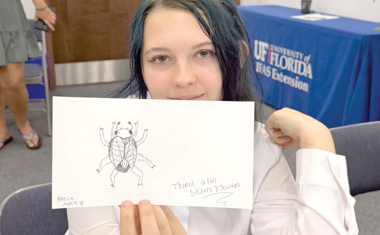 A Columbia County 4-H Arachnerds member shows off her original beetle-inspired creation. Designing imaginary bugs gave club members a chance to combine creativity with what they were learning about entomology and arthropod characteristics. (COURTESY)