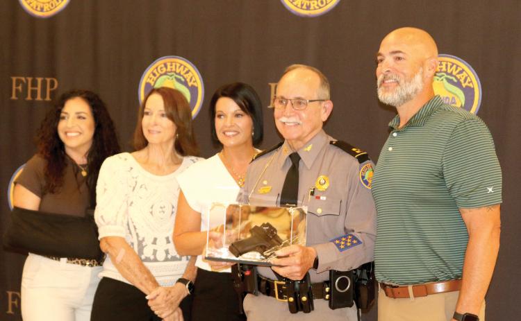 Florida Highway Patrol Troop B District Commander Mike Burroughs holds a service weapon in a box that was a presented to him as a retirement present as he is pictured with members of his family Friday. (TONY BRITT/Lake City Reporter)