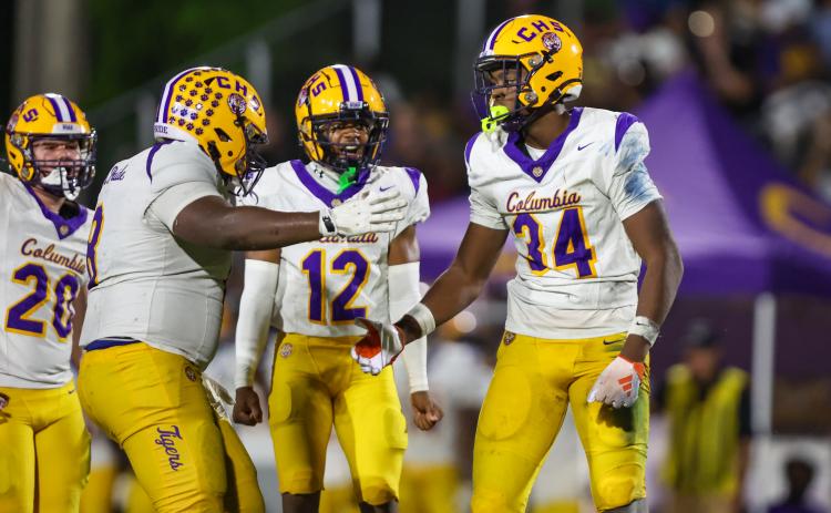Columbia defensive tackle Jaylen Underwood (8), linebacker Kaleb Williams (12) and defensive end Mikel Morgan (34) celebrate after a play against Trinity Christian last Friday. (GARY LLOYD MCCULLOUGH/Special to the Reporter)