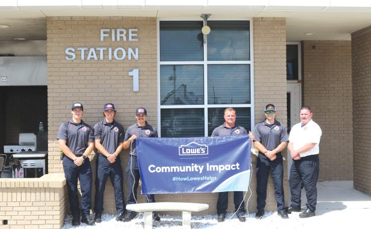 Lake City firefighters Sam Watkins (from left), Nick Chesser, Jerney Morgan, Daniel Dohrn, Gavin McAllister and Lt. Robert Oliver hold a banner promoting the Lowe’s grant that is funding future renovations of the Lake City Fire Department living quarters. (TONY BRITT/Lake City Reporter)