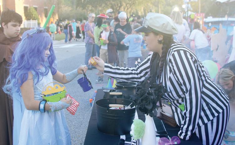 Lyndsey Weissendorn receives candy from Florida Department of Transportation employee Kaitlyn Hill during a previous year’s trunk-or-treat event at the District 2 office. (FILE)