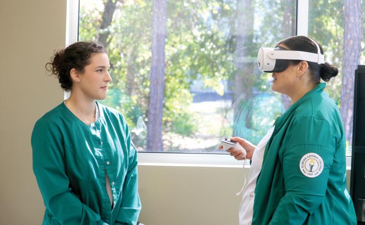Florida Gateway College nursing student Heather Bellot (left) looks at fellow student Mallory Bedenbaugh as Bedenbaugh utilizes an Occulus virtual reality headset for a training session. (TONY BRITT/Lake City Reporter)