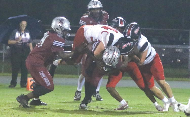 Fort White linebacker Kayden Ireland hangs on the back of Madison County quarterback Chad Mitchell as other Indians converge last Thursday. (MORGAN MCMULLEN/Lake City Reporter)