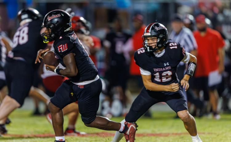 Fort White quarterback Carter Wheeler (12) hands the ball off to running back John’l Lawson during last week’s 29-22 win over Lafayette. (JACK HOWDESHELL/Lake City Reporter)
