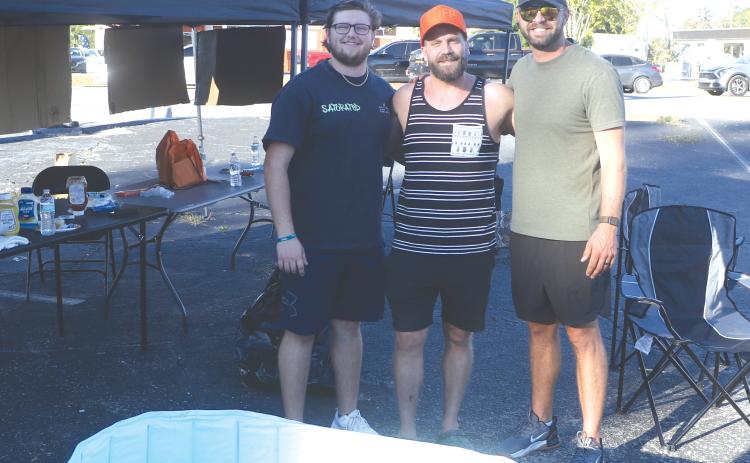 Tucker Williams (from left), Zach Zedar and Shayne Barber gather under the shade of their tent on the corner of SW Baya Avenue and SW Main Boulevard. The trio offered free hot dogs, Bibles and prayers for passers by on Thursday. (MORGAN MCMULLEN/Lake City Reporter)