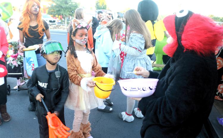 Parker Smith (from left), 5, and Jade Smith, 7, collect candy from Luz Perez of Marie’s Mexican Treats while at the Texas Roadhouse Trunk or Treat event on Tuesday evening. (TONY BRITT/Lake City Reporter)