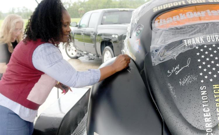 Lake City Vice Mayor Chevella Young signs the Thank Our First Responders car during its stop Thursday at the Columbia County Sheriff’s Office. (TONY BRITT/Lake City Reporter)