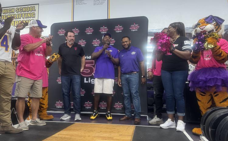 Columbia coach Brian Allen (middle) speaks alongside a T-Mobile representative (left) and Columbia offensive line coach Anthony Newton (right) while surrounded by players, staff and cheerleaders as the football program is presented with $25,000 after advancing to the final 40 in the T-Mobile Friday Night 5G Lights competition on Thursday. CHS is now in the running for a $250,000 prize. (JAMIE WACHTER/Lake City Reporter)