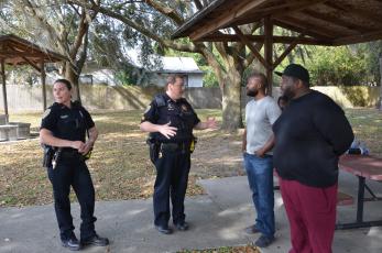 LCPD Sgt. Mike Lee speaks with Sylvester Warren and his brother, Michael Warren, after a tense exchange at a local park. Sylvester Warren gathered a group to block a public works employee from pressure washing benches, saying it would be a meaningless gesture that fails to improve the park in a meaningful way. (CARL MCKINNEY/Lake City Reporter)