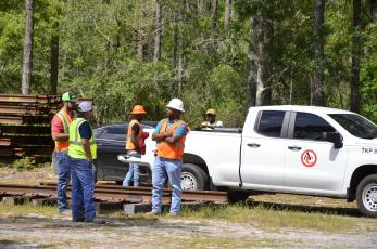 A construction crew gathers Thursday on the north side of U.S. Highway 90, where work is underway to construct a rail spur connecting the North Florida Mega Industrial Park to cities throughout the region. A stack of railing is visible in the back left. The project has been years in the making, with county officials frequently vowing it will pave the way for major economic growth in the community. (CARL MCKINNEY/Lake City Reporter)