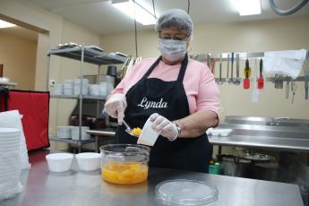 Lynda Cauley spoons up some Mandarin oranges as she prepares food at the Columbia County Senior Services Lifestyle Enrichment Center kitchen. (TONY BRITT/Lake City Reporter)