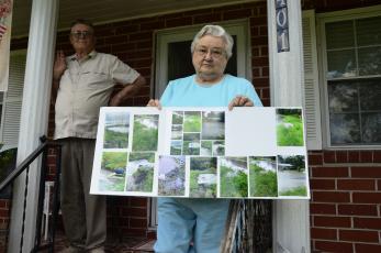 Ona and Donald Strand show pictures of the most recent flood on their property by Gwen Lake. The lakeside neighborhood’s ongoing watery woes have prompted the city to pursue a project to improve drainage in the area. (CARL MCKINNEY/Lake City Reporter)