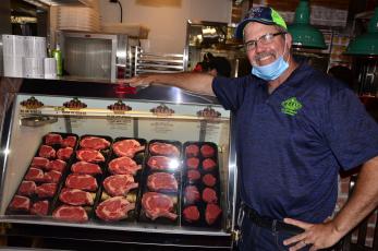 Steve Hale, managing partner for the Lake City Texas Roadhouse, poses alongside an assortment of meats ahead of the opening of the chain’s new location. (CARL MCKINNEY/Lake City Reporter)