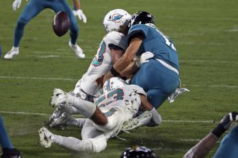 Jacksonville Jaguars quarterback Gardner Minshew, right, fumbles the ball as he is hit by Miami Dolphins outside linebacker Andrew Van Ginkel, left, and middle linebacker Kyle Van Noy during Thursday's game in Jacksonville. (STEPHEN B. MORTON/Associated Press)