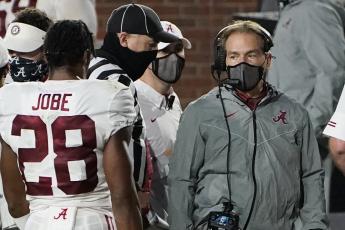 A masked Alabama coach Nick Saban speaks with defensive back Josh Jobe (28) during a game against Mississippi on Oct. 2 in Oxford, Miss. (ROGELIO V. SOLIS/Associated Press)