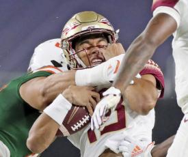 Florida State quarterback Jordan Travis (13) is tackled by a Miami player on Sept. 26 in Miami Gardens. (AL DIAZ/Miami Herald via AP)