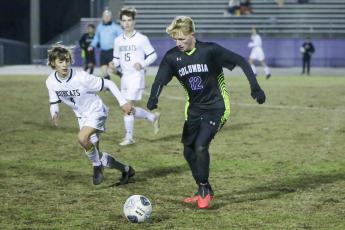 Columbia’s Zack Strickland dribbles up the field while Buchholz’s Riley Smith gives chase during Wednesday’s District 2-6A semifinals. (BRENT KUYKENDALL/Lake City Reporter)