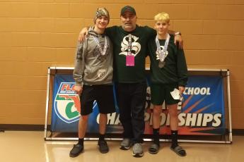 Suwannee wrestlers Timothy Jolicoeur (left) and Austin McKinney (right) stand with coach John Wainwright after reaching the medal stand at the Class 1A state meet on Saturday. (COURTESY)