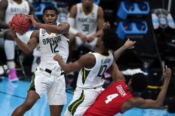 Baylor guard Jared Butler (12) passes over teammate guard Adam Flagler (10) and Houston forward Justin Gorham (4) during the Final Four semifinal game at Lucas Oil Stadium on Saturday in Indianapolis. (MICHAEL CONROY/Associated Press)