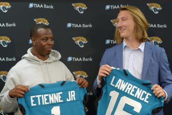 Former Clemson teammates and now Jaguars teammates running back Travis Etienne, left, and quarterback Trevor Lawrence pose with their new teal jerseys prior to an introductory press conference on April 30 at TIAA Bank Field in Jacksonville. (BOB SELF/TNS)