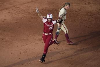 Oklahoma's Jana Johns (20) celebrates as she runs past Florida State's Josie Muffley after hitting a home run during the third inning of Game 2 of the Women's College World Series softball championship series on Wednesday in Oklahoma City. (SUE OGROCKI/Associated Press)