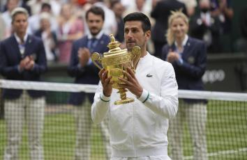 Novak Djokovic holds his winner's trophy and celebrates his victory over Matteo Berrettini in the Wimbledon men's singles final match on Sunday in London. (ALBERTO PEZZALI/Associated Press)
