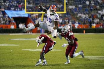 Florida quarterback Anthony Richardson (15) hurdles Florida Atlantic defensive back Justin McKithen (11) and safety Armani-Eli Adams (30) on Sept. 4 in Gainesville. (JOHN RAOUX/Associated Press))