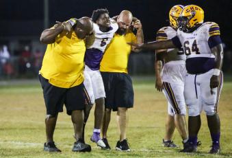 Columbia’s Tray Tolliver is helped off the field by defensive line coach Mark Campbell and co-defensive coordinator John Woodley during last Friday’s game against Madison County. (BRENT KUYKENDALL/Lake City Reporter)