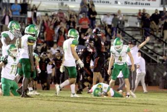 Suwannee kicker Braxtyn Green lays on the ground in dejection after his overtime field goal sailed wide left as Bishop Kenny players celebrate. (PAUL BUCHANAN/Special to the Reporter)