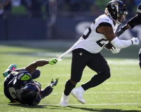 Jacksonville Jaguars running back James Robinson, right, is grabbed by his jersey by Seattle Seahawks free safety Quandre Diggs on Oct. 31 in Seattle. (STEPHEN BRASHEAR/Associated Press)
