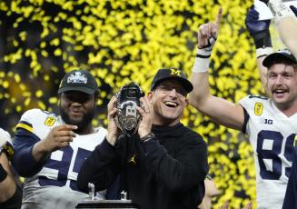Michigan coach Jim Harbaugh celebrates with the team after winning the Big Ten championship against Iowa, 42-3, on Dec. 4 in Indianapolis. It was the Wolverines' first Big Ten title in 17 years, which clinched a berth in the College Football Playoff. (AP File)