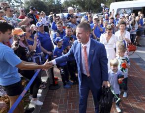 New Florida head coach Billy Napier shakes hands with fans as he and his family arrive at Ben Hill Griffin Stadium on Sunday in Gainesville. (BRAD MCCLENNY/The Gainesville Sun via AP)