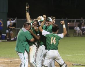 Suwannee coaches and player swarm Carston Palmer after he scored the game-winning run against Clay in the Region 1-4A semifinals on Saturday night. (PAUL BUCHANAN/Special to the Reporter)