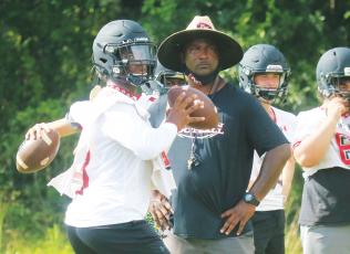 Former Fort White quarterback Tyler Jefferson drops back to pass while former head coach Demetric Jackson looks on during a practice in 2020. (FILE)