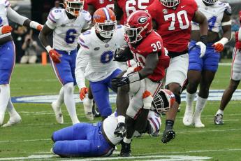 Georgia running back Daijun Edwards is stopped by Florida linebacker Antwaun Powell-Ryland Jr., bottom and safety Trey Dean III (0) during Saturday’s game in Jacksonville. (JOHN RAOUX/Associated Press)