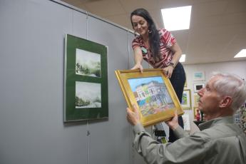 Sheila Carr, Gateway Art Gallery Curator, is assisted by Jim Riley as she hangs artwork for the upcoming ‘The Art Of Matter’ exhibit which will be featured in the gallery during January. (TONY BRITT/Lake City Reporter)